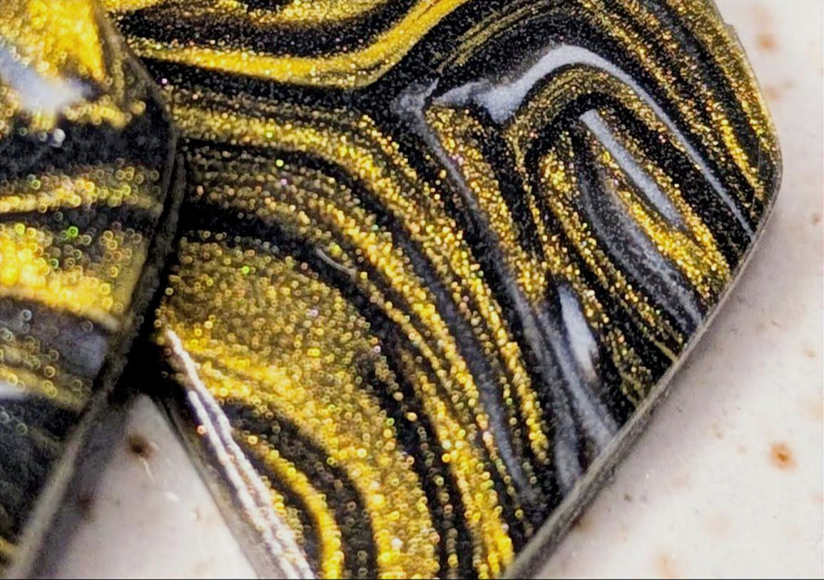 Close-up of a marbled surface with gold and black patterns on a textured background